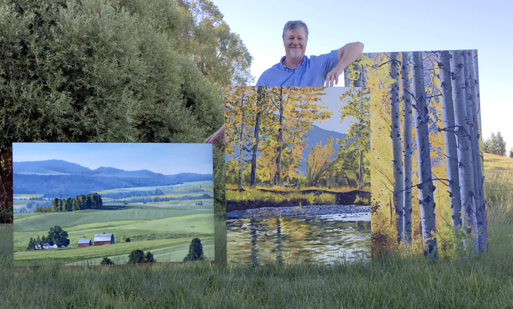 Andy Sewell posing with his paintings