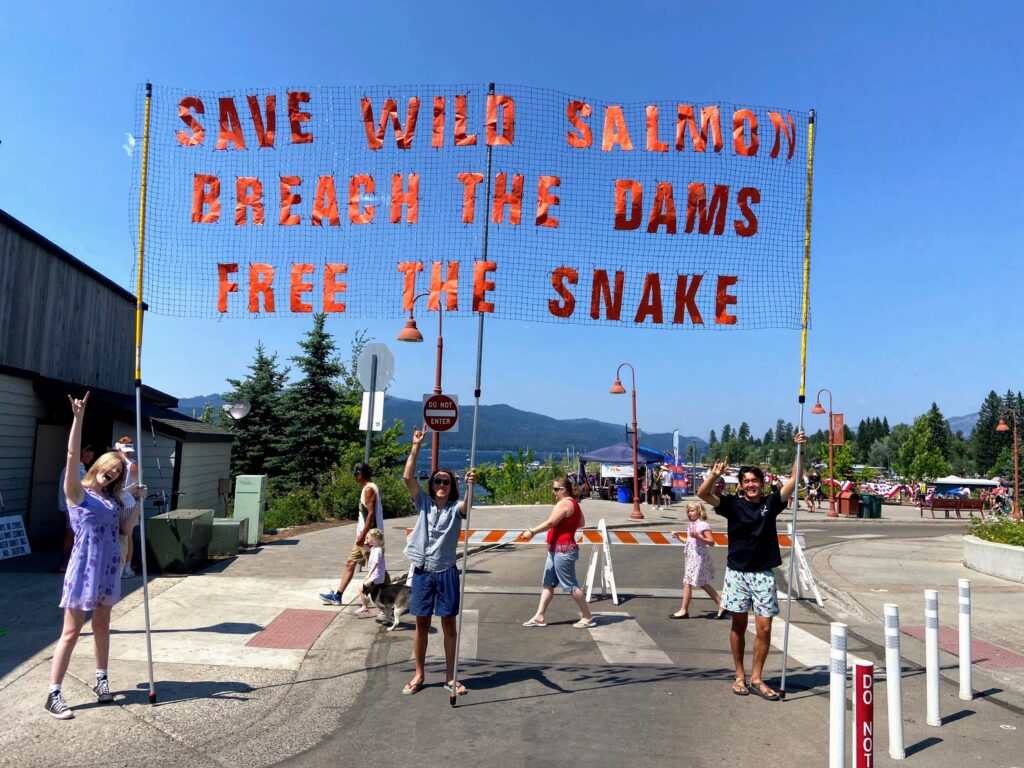 Youth Salmon Protectors hold a banner reading "Save Wild Salmon Breach the Dams Free the Snake" in McCall, ID